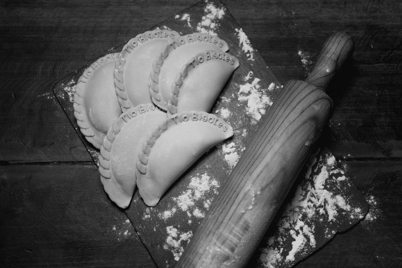 Empanadas crudas y palote de madera