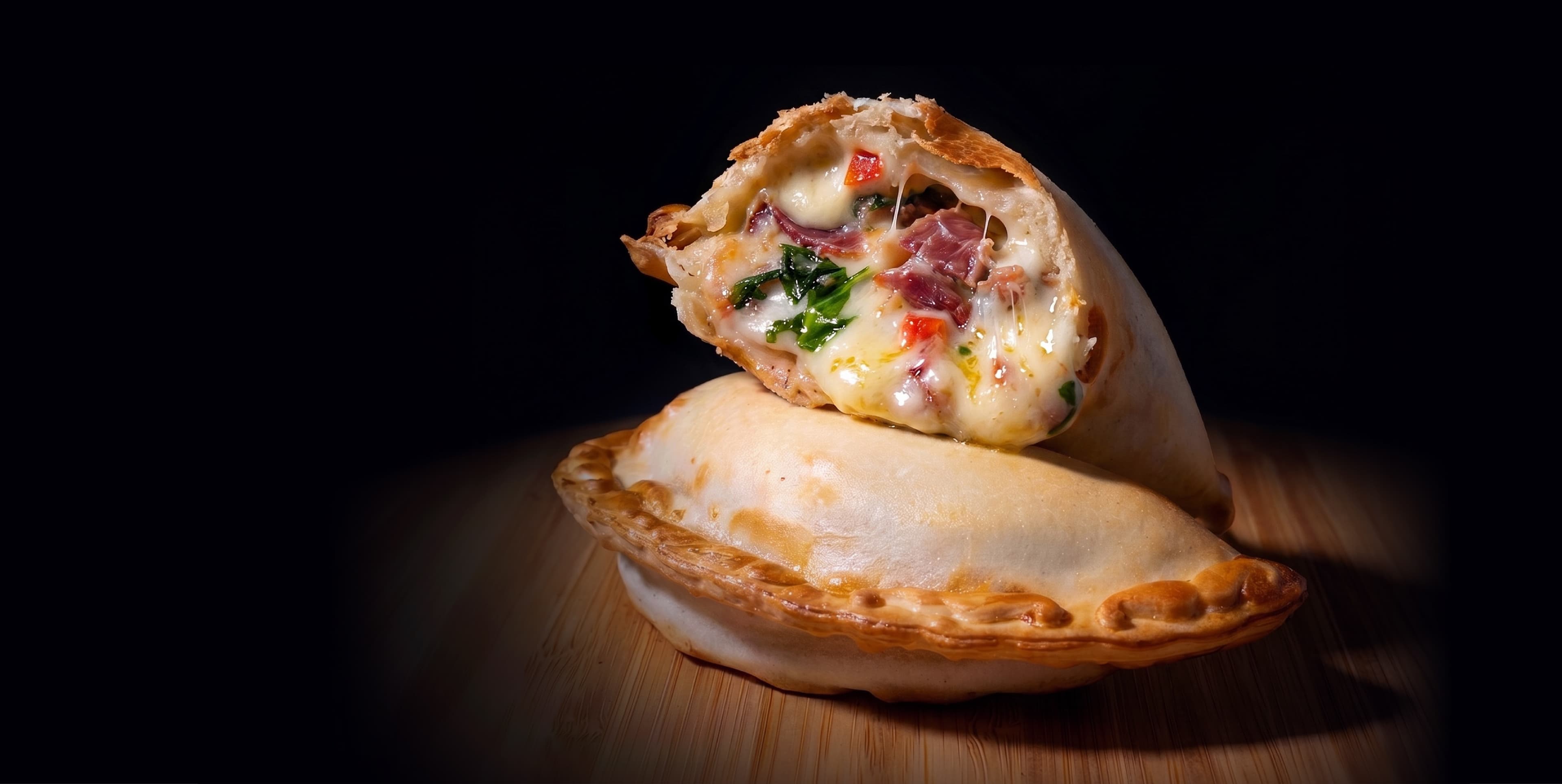 Empanada de jamón y queso cortada al medio, mostrando el relleno